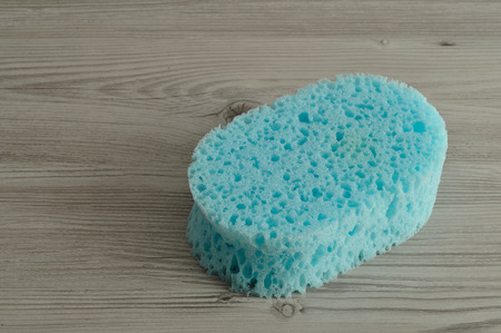 A blue bath sponge isolated on a wooden background