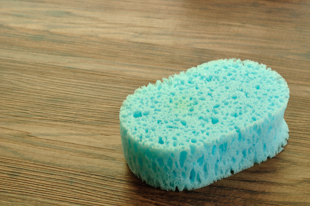 A blue bath sponge isolated on a wooden backgroundの写真素材