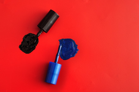 Two brushes of nail polish bottles displayed on a red background. Top view.の写真素材