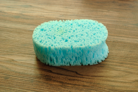 A blue bath sponge isolated on a wooden background