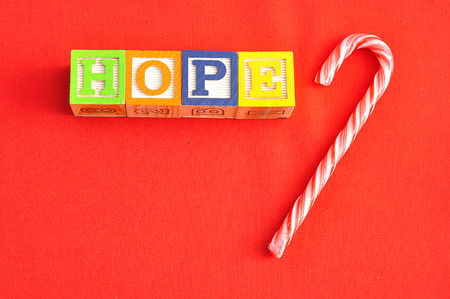 Hope spelled with Alphabet blocks on a red background with a candy cane