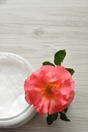 Body lotion in a plastic container with a pink rose top viewの写真素材
