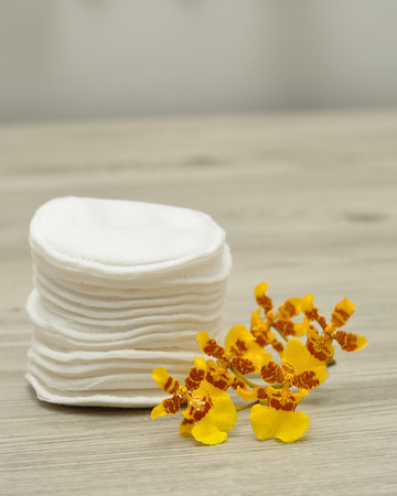 A stack of cotton pads with yellow orchidsの写真素材