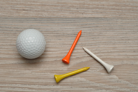 A golf ball with tee's isolated on a wooden backgroundの写真素材