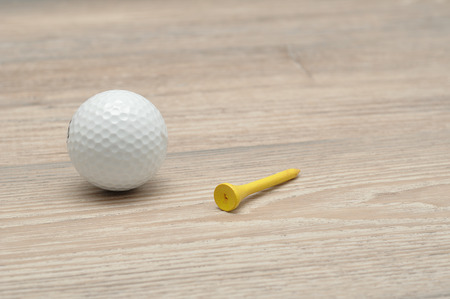 A golf ball with tee's isolated on a wooden backgroundの写真素材