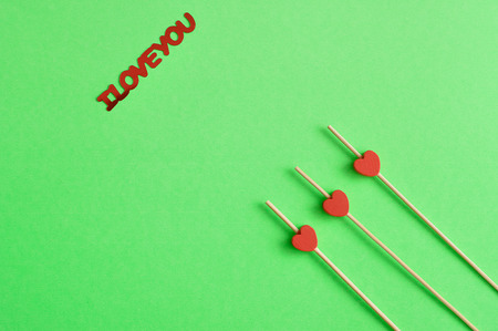 Valentine's Day. Three red hearts on sticks with a green background an I love you in red letteringの写真素材