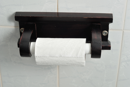 A wooden toilet paper roll holder with a roll of toilet paperの写真素材