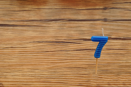 A birth day candle isolated on a wooden background. Blue number sevenの写真素材