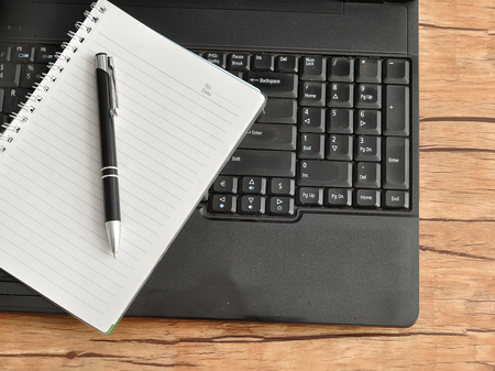 Laptop with a notebook and a penの写真素材
