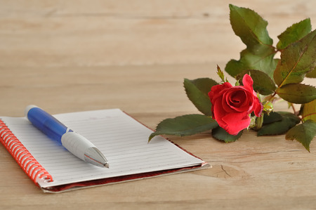 A notebook and pen with a red roseの写真素材