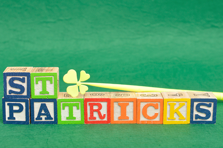 St Patrick's day spelled with colorful alphabet blocks displayed with a four leaf clover on a green backgroundの写真素材