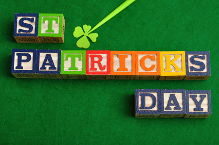 St Patrick's day spelled with colorful alphabet blocks displayed with a four leaf clover on a green backgroundの写真素材