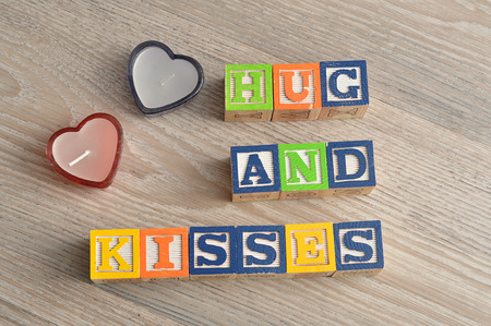 Valentine's Day. Hugs and kisses Spelled with colorful alphabet blocks and two red heart shape candlesの写真素材