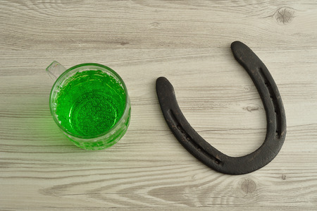 Green liquid in a beer mug displayed with a horseshoe for St. Patrick's dayの写真素材