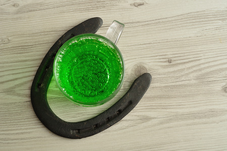 Green liquid in a beer mug displayed with a horseshoe for St. Patrick's dayの写真素材
