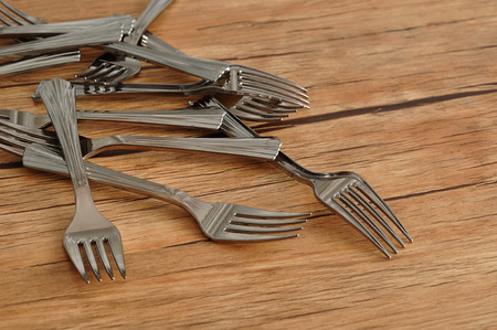 A pile of cake forks isolated on a wooden background