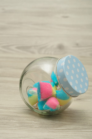 A glass jar with a blue polka dot lid half filled with  candyの写真素材