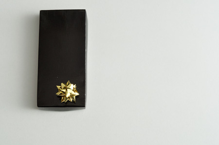 A black gift box with a gold bow isolated on a white backgroundの写真素材