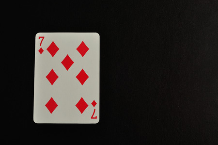 Playing card. Seven of diamond isolated on a black background