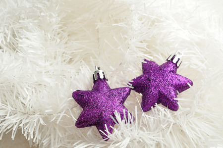 Two purple stars to decorate a Christmas tree isolated on white tinsel の写真素材