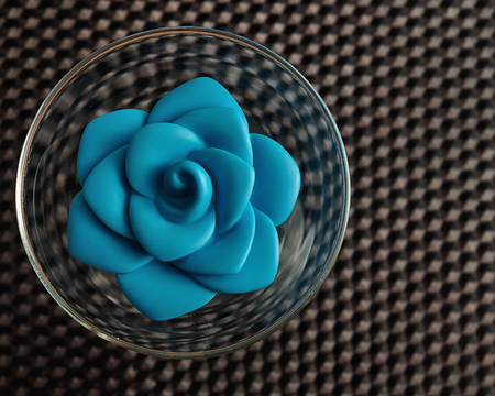 A blue plastic rose in a glass bowl used for decorationの写真素材