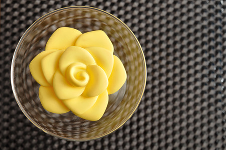 A yellow plastic rose in a glass bowl used for decorationの写真素材
