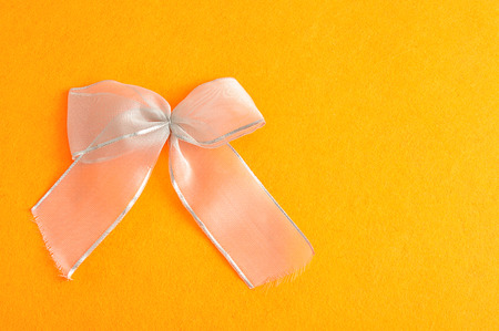 A silver bow isolated against an orange backgroundの写真素材