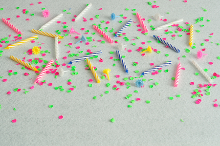 Birthday candles displayed on a white background littered with green and pink confettiの写真素材