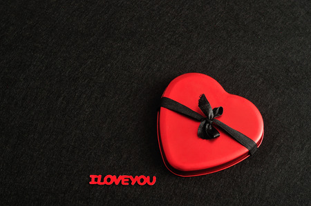 Valentines day. A red heart tied with a black ribbon isolated against a black background with the words I love youの写真素材