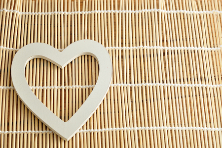 Valentine's Day. A white wooden heart isolated against a bamboo backgroundの写真素材