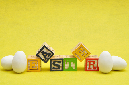 Easter spelled with colorful alphabet blocks displayed with white easter eggsの写真素材