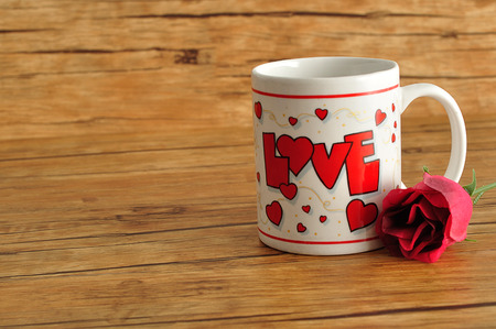 Valentine's Day. A white mug with the word love on it with an artificial roseの写真素材