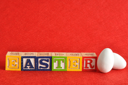 Easter spelled with colorful alphabet blocks displayed with white easter eggsの写真素材