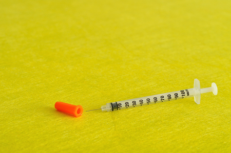 An injection isolated against a yellow backgroundの写真素材