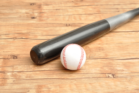 A baseball bat and ball isolated on a wooden backgroundの写真素材