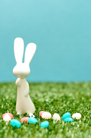 A white plastic bunny figurine displayed with jelly beansの写真素材