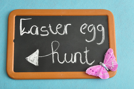A blackboard with the words easter egg hunt with a pink butterflyの写真素材