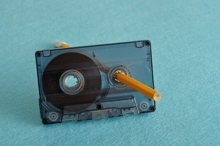 An old tape cassette with a pencil isolated on a blue backgroundの写真素材