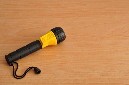 A yellow and blue plastic flashlight isolated against a wooden backgroundの写真素材