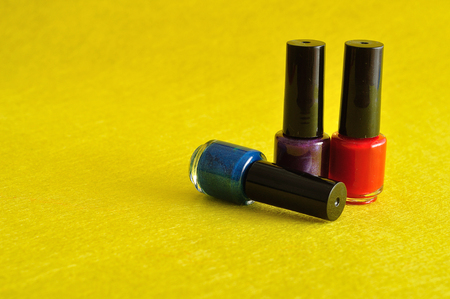 Bottles of colorful nail polish displayed against a yellow backgroundの写真素材