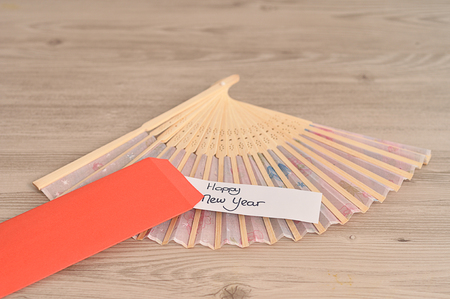 Chinese New Year design. A red envelope for money in the Chinese New Year isolated  with a hand fan and a note  Happy New Yearの写真素材