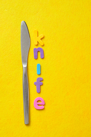 The word knife displayed with a knife on a yellow backgroundの写真素材