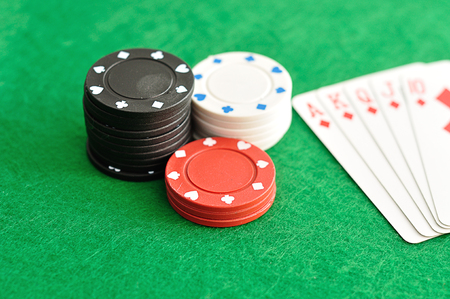 A stack of poker chips with a royal flush that is out of focus
