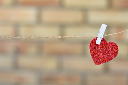 A red heart shape hanging on a ropeの写真素材