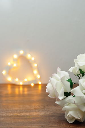 A bunch of white artificial roses with an out of focus light heart shapeの写真素材