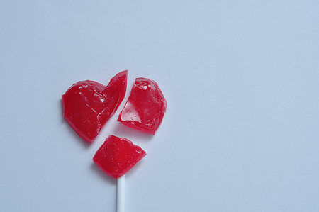 A broken red heart lollipop symbolizing a broken heartの写真素材