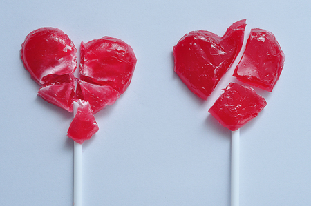 Two broken red heart lollipops symbolizing broken heartsの写真素材