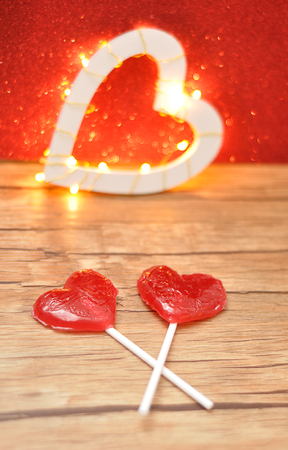 Two red heart shape lollipop isolated against a red background with an out of focus light heart shapeの写真素材