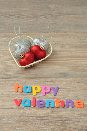 A wire basket filled with silver and red heart shape baubles and the words happy valentineの写真素材