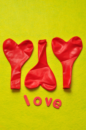 Three red heart shape balloons and the word love on a yellow backgroundの写真素材